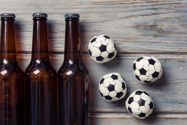 Garrafa de cerveja com bolas de futebol em um fundo de madeira