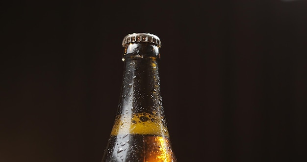 Garrafa de cerveja fria sobre um fundo preto Condensado