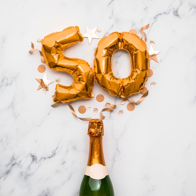 Foto garrafa de champanhe com balão de ouro número 50 conceito de aniversário de festa minimalista