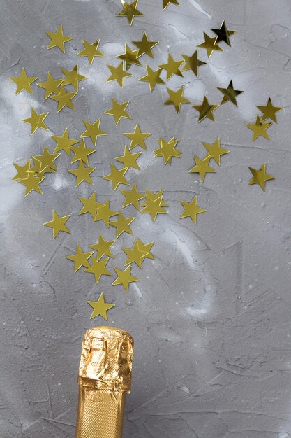 Garrafa de champanhe com estrelas de confete de ouro Conceito para aniversário de natal ou casamento