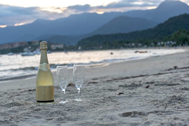 Garrafa de champanhe com taças na praia