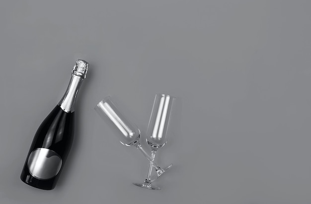 Garrafa de champanhe e copos em fundo cinza de moda com lugar para texto