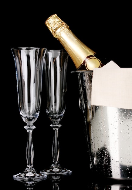 Garrafa de champanhe em balde com gelo e taças pretas