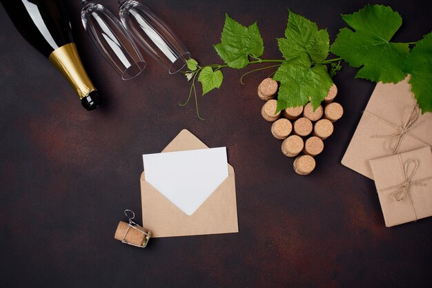 Garrafa de champanhe, gape bando de cortiça com folhas, dois copo de vinho, envelope e carta sobre fundo enferrujado.