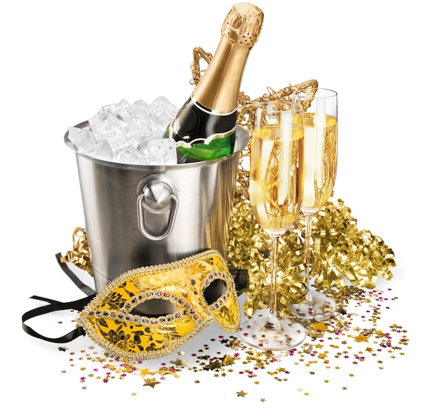 Garrafa de champanhe no balde de gelo com taças, serpentinas e máscara