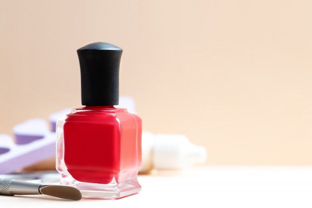 Garrafa de esmalte vermelho e ferramentas de manicure em uma tabela.