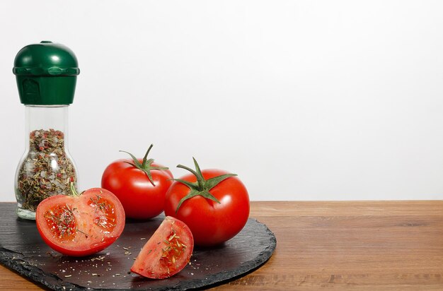 Garrafa de especiarias e tomates frescos na mesa da cozinha