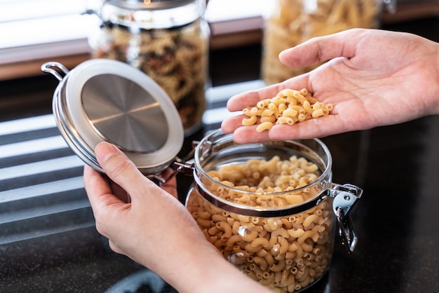 Garrafa de mão aberta de macarrão na cozinha