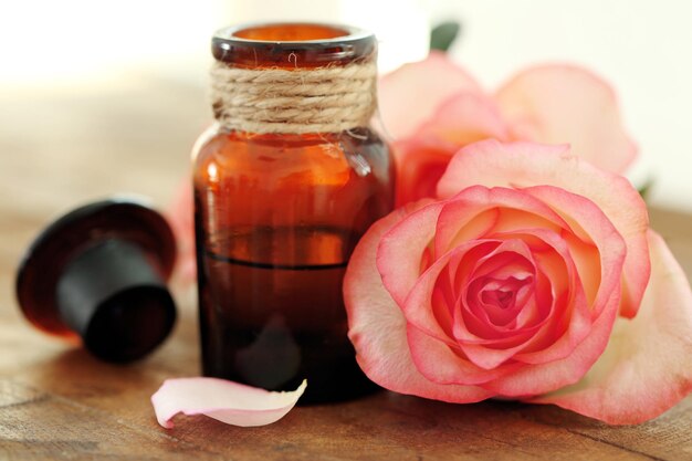 Garrafa de óleo de aroma com rosas na mesa de madeira