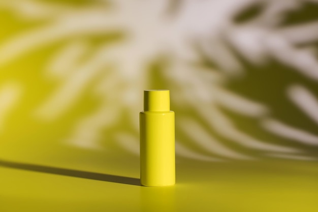 Garrafa de plástico em branco de cosméticos naturais e padrão de sombras em tons de luz amarela