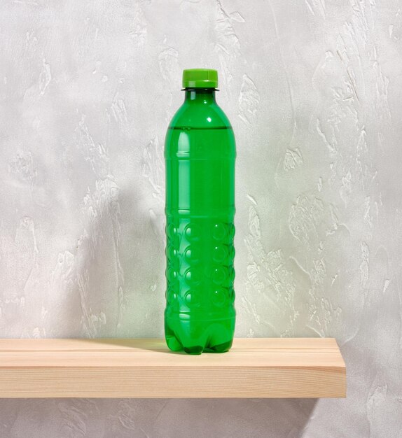 Garrafa de plástico verde com água doce sobre um fundo cinza Equilíbrio da água Conceito de poluição e proteção ambiental
