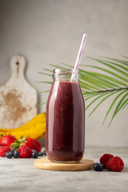 Garrafa de smoothie de frutas vermelhas em um copo Bebida saudável de morango, banana e mirtilo Copiar espaço