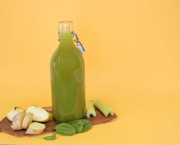 Garrafa de suco de espinafre e placa de cozinha com legumes e frutas. copie o espaço.