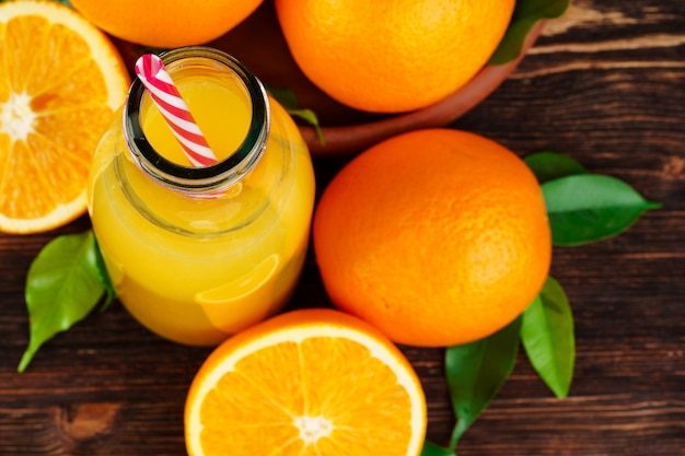 Garrafa de suco de laranja com laranjas na mesa de madeira