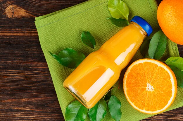 Garrafa de suco de laranja com laranjas na mesa de madeira