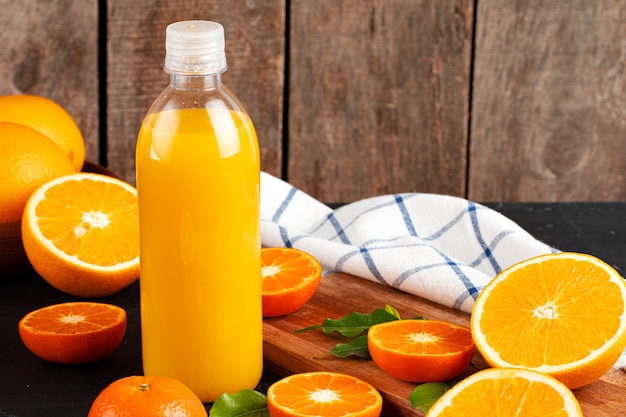 Foto garrafa de suco de laranja e laranjas frescas na mesa