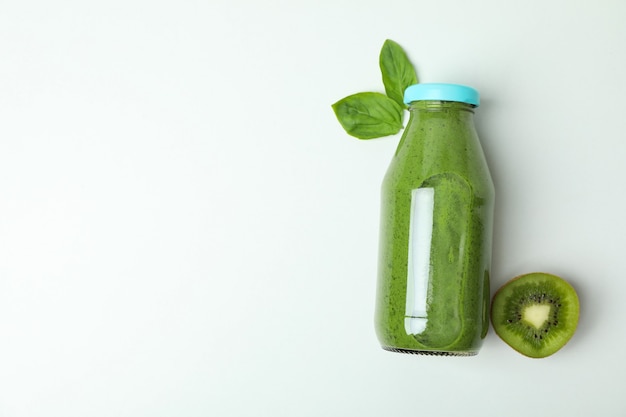 Garrafa de suco verde, kiwi e folha de manjericão no fundo branco