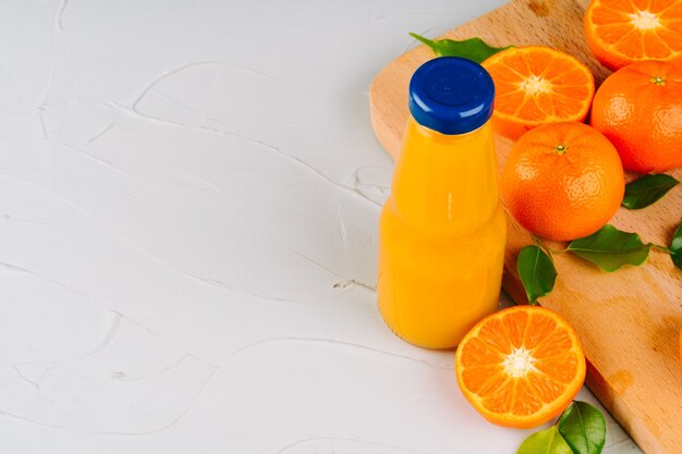 Garrafa de vidro de suco de laranja com metades de laranjas maduras