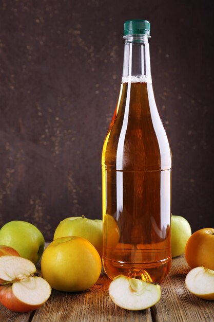 Garrafa de vinagre de maçã com maçãs frescas na mesa de madeira