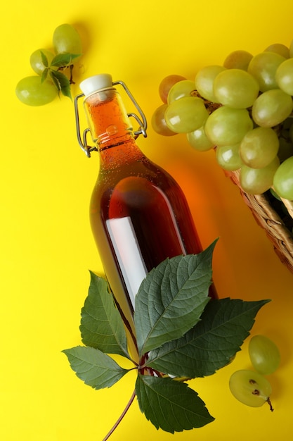 Garrafa de vinagre e cesta com uva em fundo amarelo