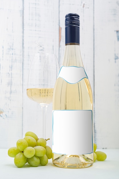 Foto garrafa de vinho branco com etiqueta. copo de vinho e uva. maquete de garrafa de vinho.