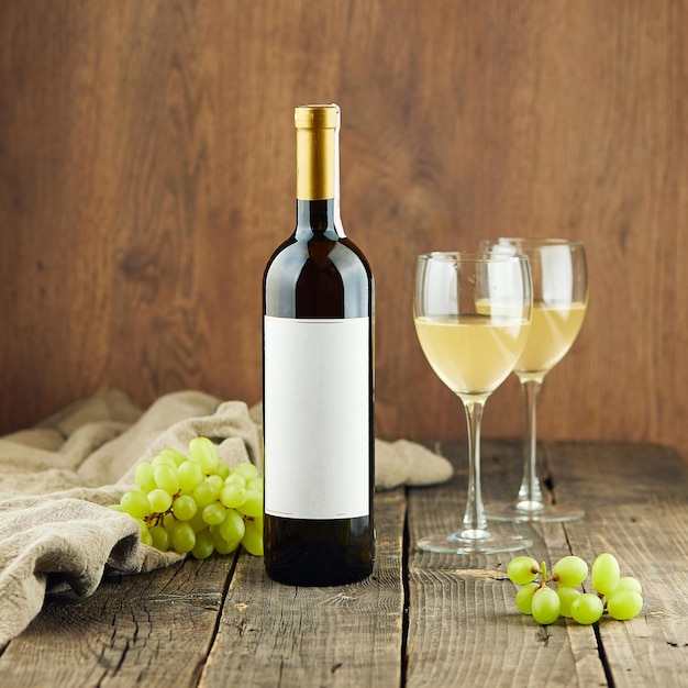 Garrafa de vinho caro com etiqueta em branco e uvas na mesa
