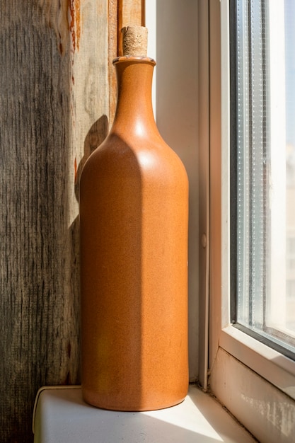 Foto garrafa de vinho de barro no peitoril da janela