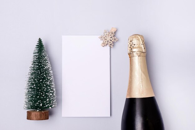 Garrafa de vinho espumante branco e árvore de Natal falsa em fundo azul festivo vista superior horizontal feriado de ano novo maquete para cima