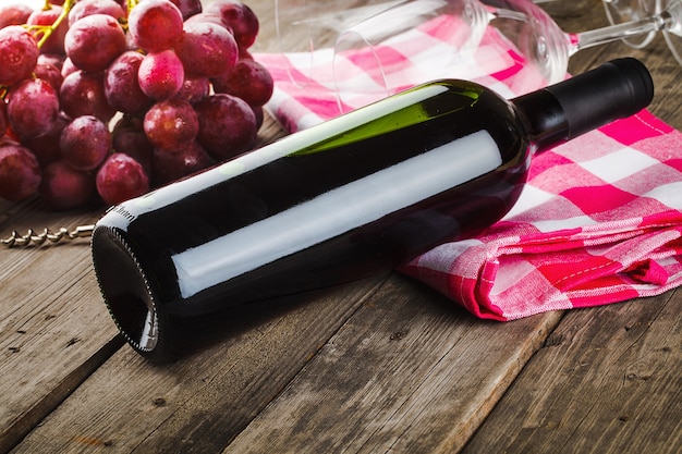 Foto garrafa de vinho saca-rolhas e uvas na mesa de madeira