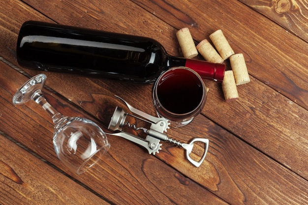 Garrafa de vinho tinto, copo de vinho e saca-rolhas na mesa de madeira