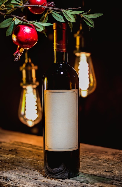 Garrafa de vinho tinto e ramo de granada em um fundo de lâmpadas vintage