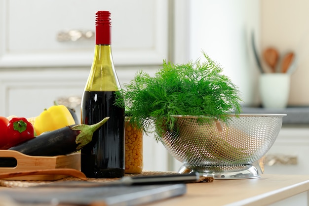 Garrafa de vinho tinto e vegetais frescos na mesa da cozinha