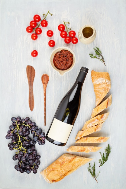 Garrafa de vinho tinto, uvas, pão e tomate para festa buffet. configuração plana tradicional francesa ou italiana. vista do topo