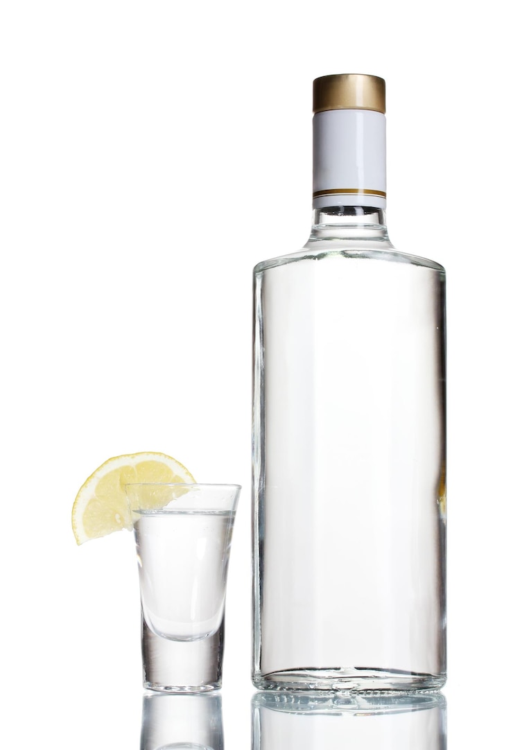 Foto garrafa de vodka e copo de vinho com limão isolado em branco