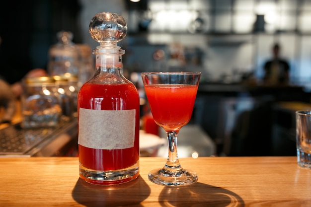 Garrafa e copo cheio de bebida alcoólica vermelha no balcão do bar