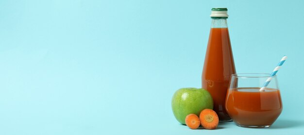 Garrafa e copo de suco e ingredientes em fundo azul isolado