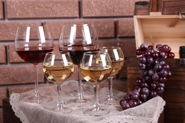 Garrafa e copos de vinho e uvas maduras na mesa no fundo da parede de tijolos
