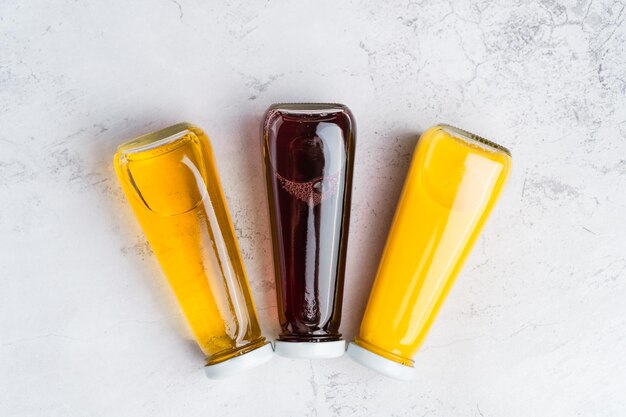 Garrafas com bebida líquida amarela e vermelha sobre fundo cinza Suco de cereja de maçã laranja