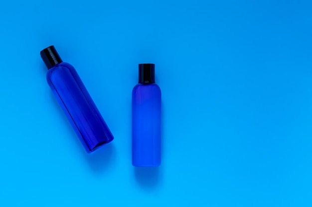 Garrafas cosméticas com xampu e loção refrescantes em um fundo azul