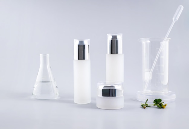 Garrafas cosméticas e frascos de laboratório em um fundo cinza