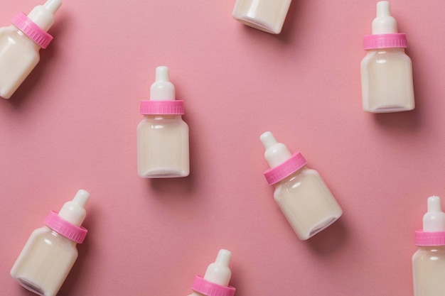 Garrafas de bebê com leite em um fundo rosa pastel