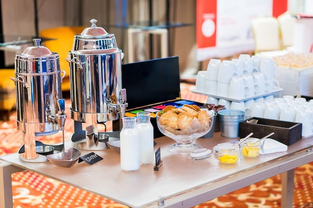Garrafas de café de copos de leite na mesa de catering no grupo de conferências de copos de cerâmica brancos vazios para co