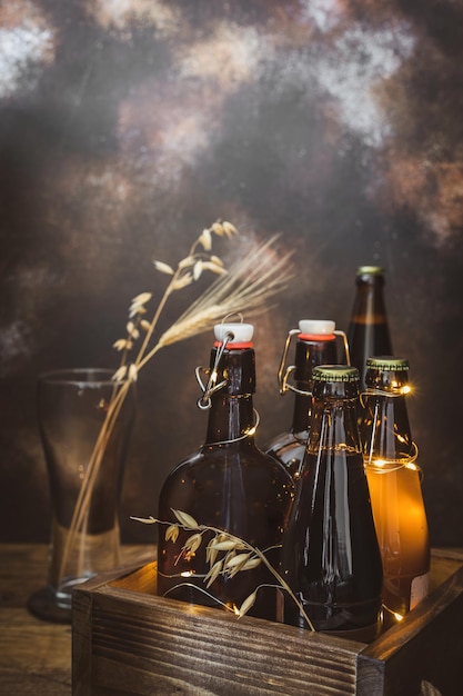 Foto garrafas de cerveja clara e escura orelhas de trigo em copo vazio e luzes em fundo marrom