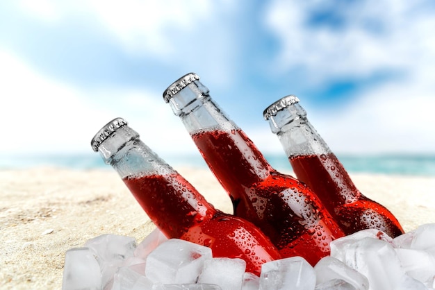 Garrafas de cerveja vermelha no gelo na praia fundo desfocado