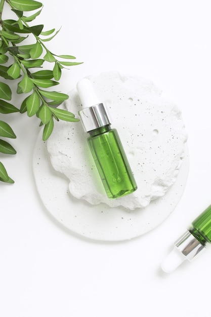 Garrafas de copos de vidro verde em pódio de concreto com folhas maquetes de recipientes cosméticos