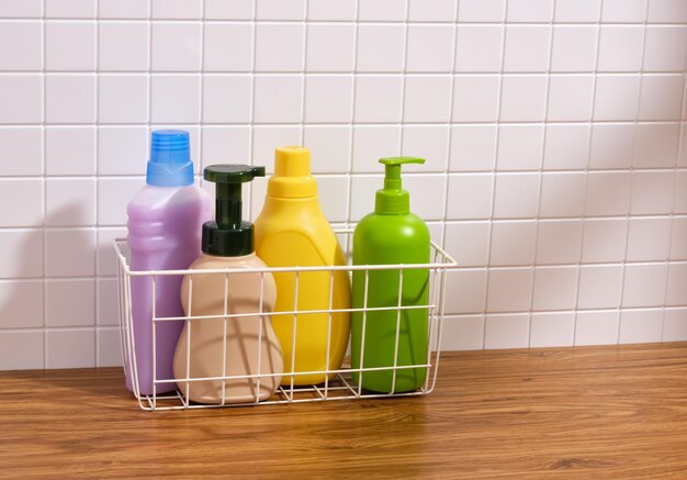 Garrafas de detergente multicoloridas num cesto branco Copiar espaço para texto