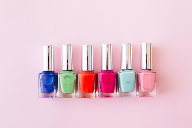 Garrafas de esmalte colorido em fundo rosa pastel conceito de manicure e pedicure espaço de cópia de vista superior plana