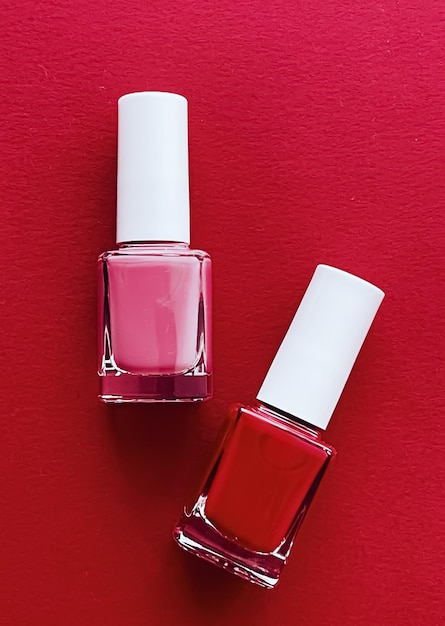 Garrafas de esmalte vermelho e rosa no conceito de manicure e cosméticos de beleza de fundo vermelho