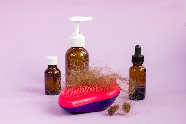 Garrafas de medicação e escova de cabelo no fundo roxo Problema de perda de cabelo