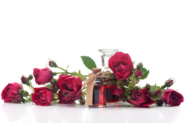 Garrafas de óleo de rosas e flores rosas em um fundo branco